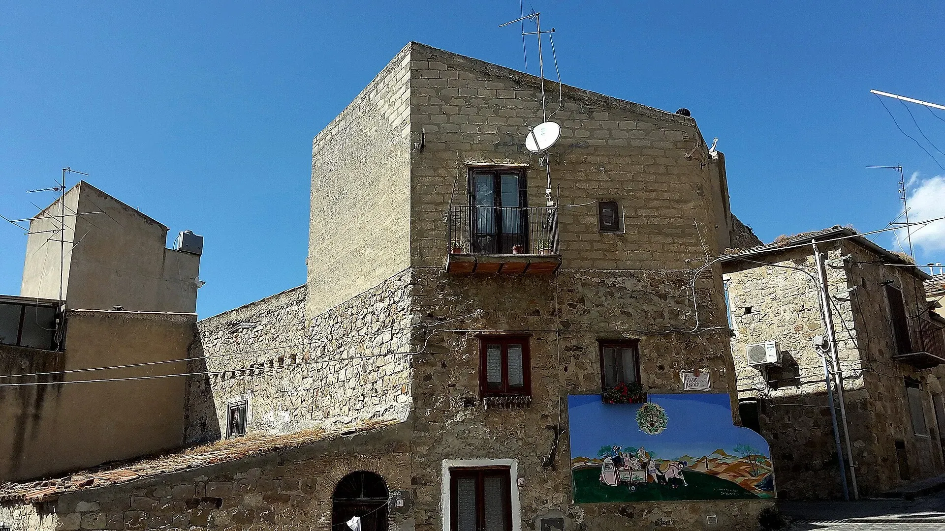 Una casa in pietra nel centro di Castellana Sicula, con un murale dipinto sulla facciata