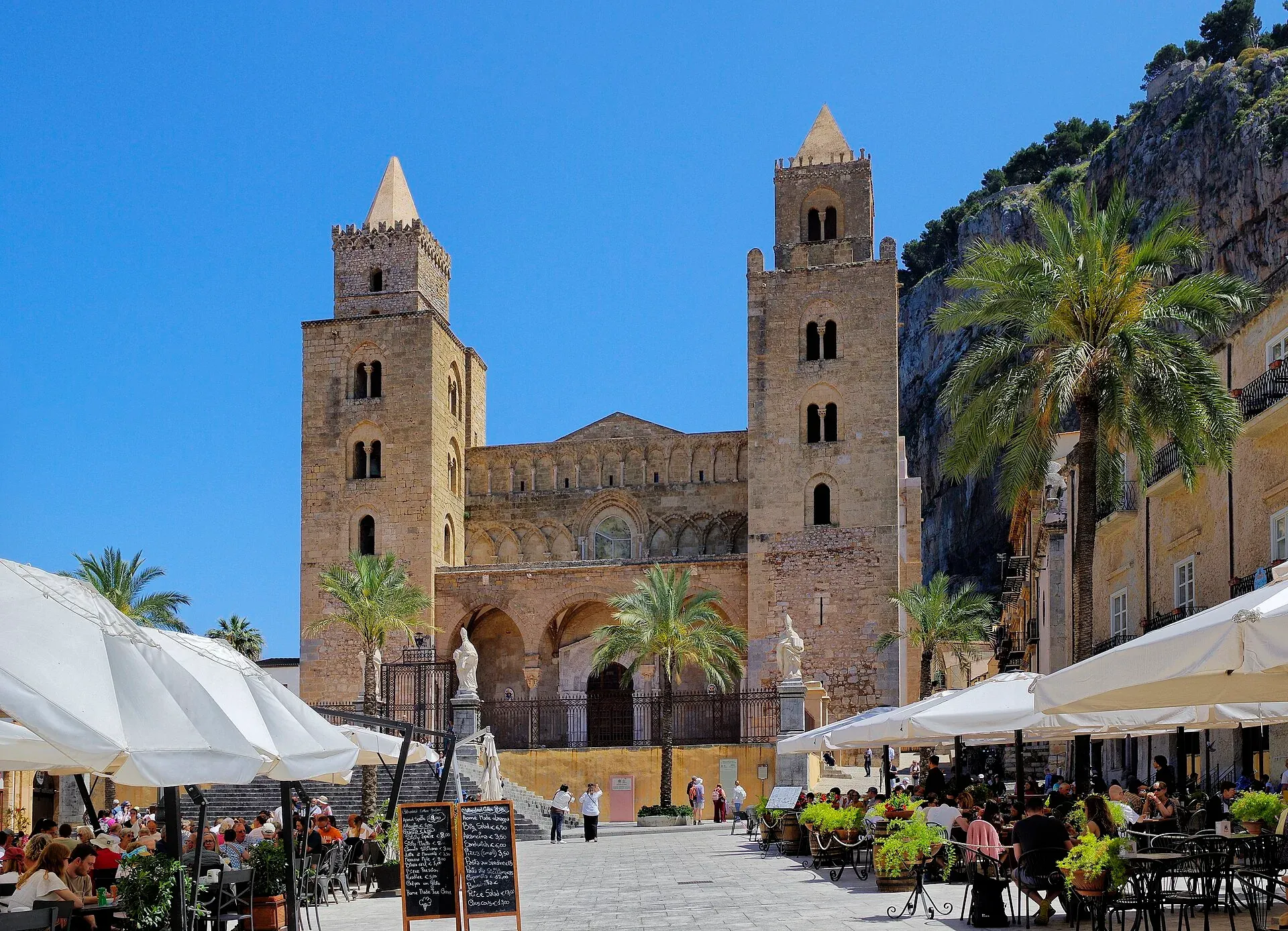 Il Duomo normanno di Cefalù con le due torri, visto dalla piazza con i tavolini all’aperto