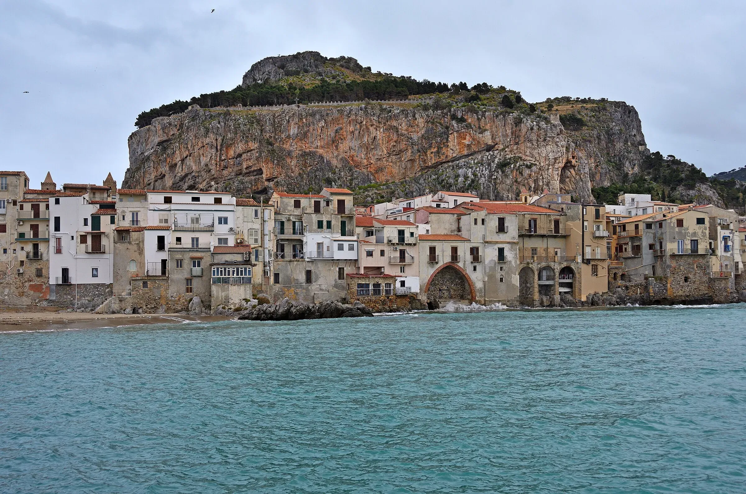 La parete della Rocca di Cefalù sopra le case affacciate sul mare