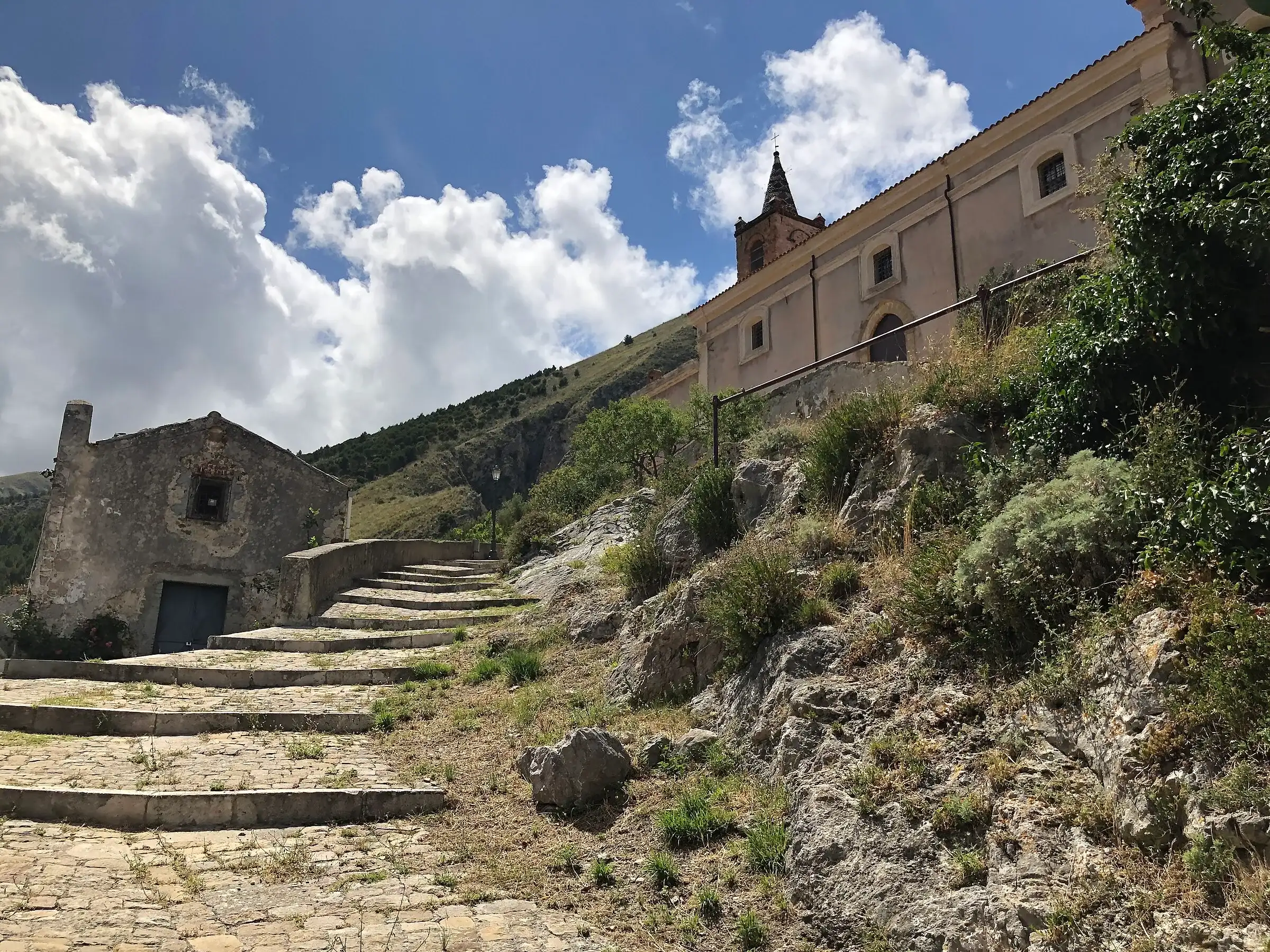 La scalinata in pietra che sale alla chiesa di Santa Maria Maggiore a Isnello, tra rocce e arbusti