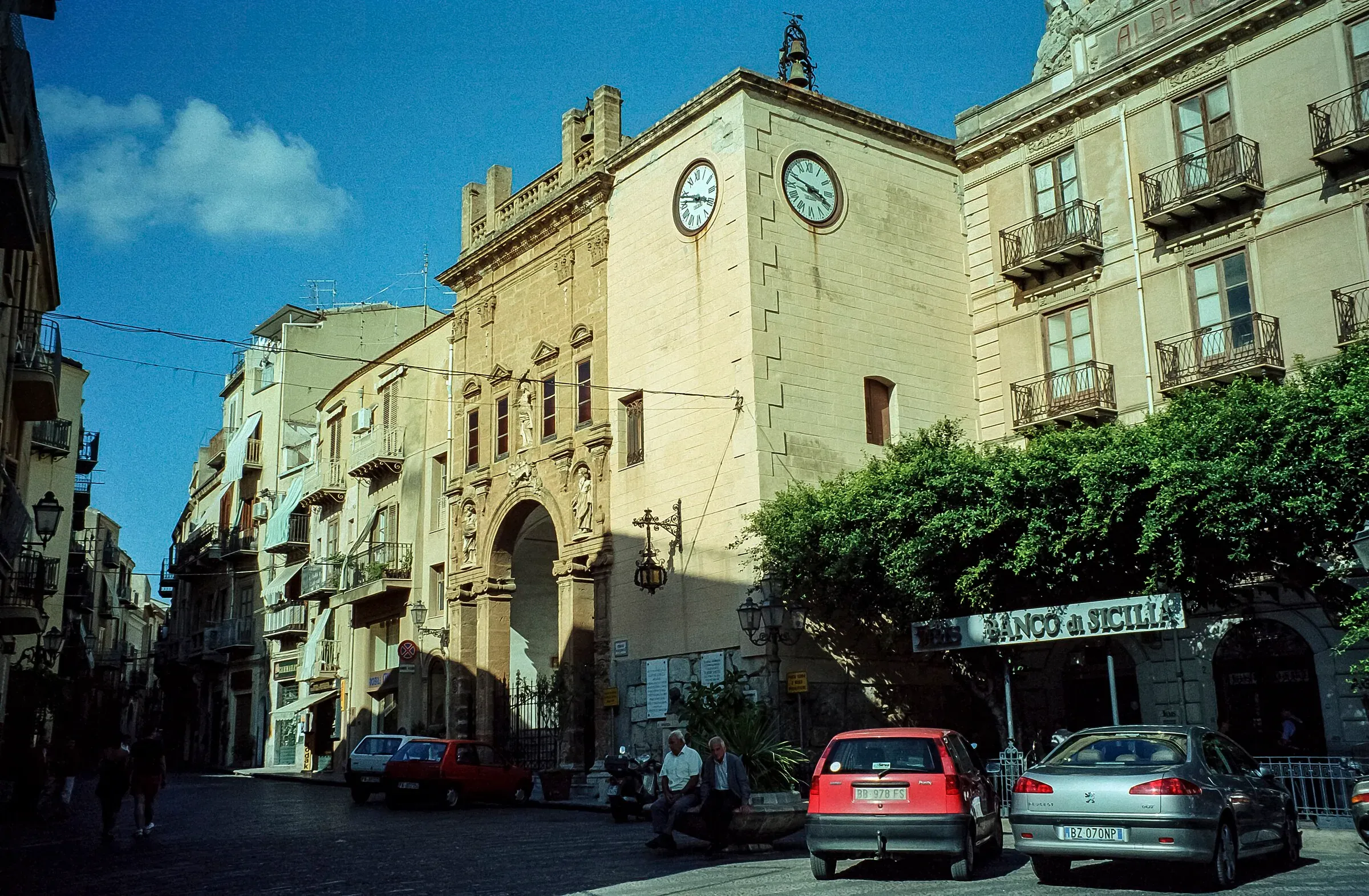 Corso Ruggero a Cefalù, con il palazzo dei due orologi e le auto parcheggiate