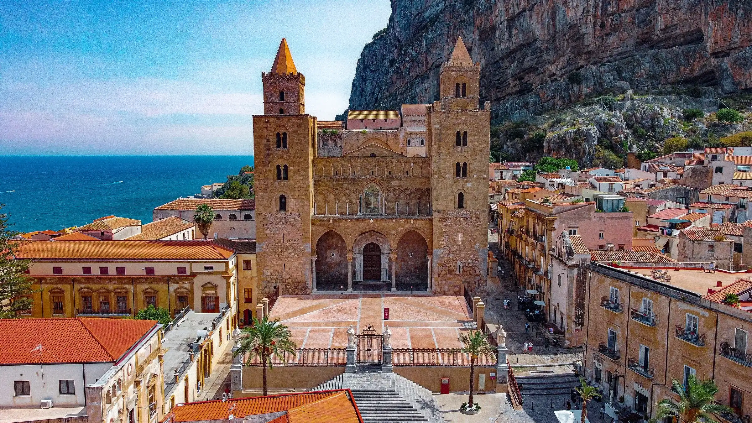 Piazza Duomo a Cefalù vista dall’alto, con la Cattedrale, le palme e la Rocca alle spalle