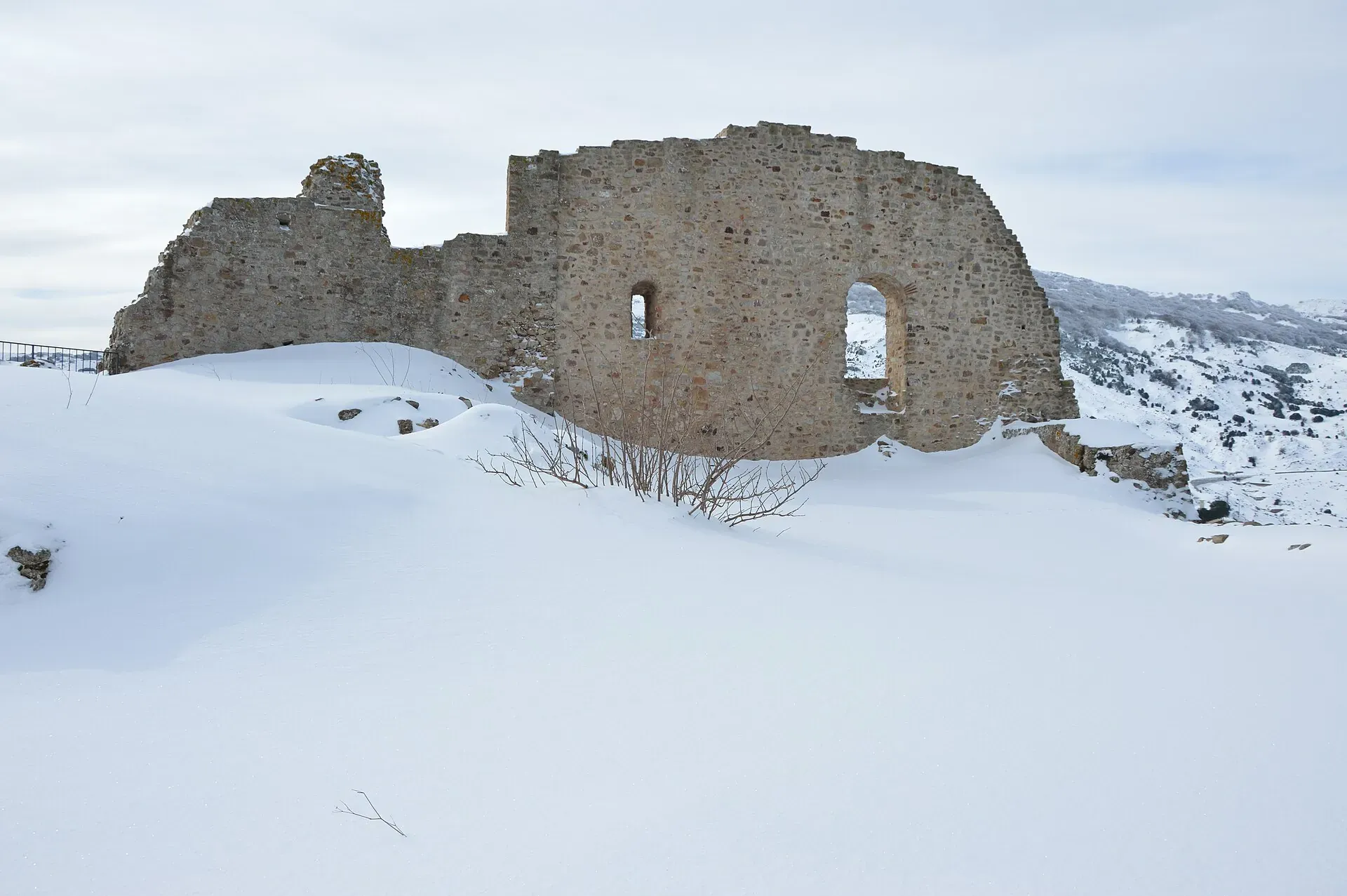 I ruderi del castello dei Ventimiglia di Geraci Siculo coperti di neve, con le montagne innevate sullo sfondo