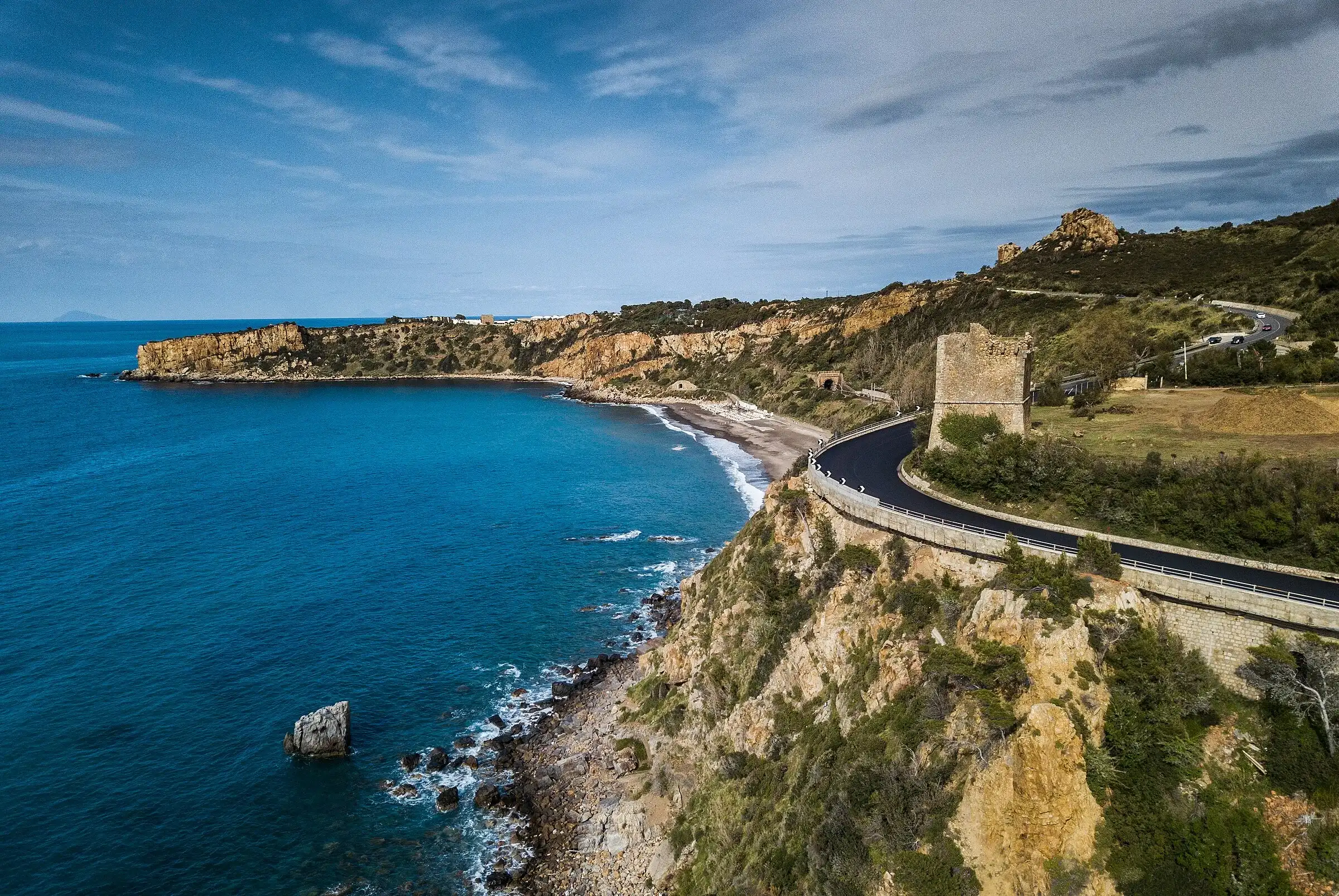 La costa di Finale di Pollina con una torre di avvistamento, la strada sul mare e la spiaggia