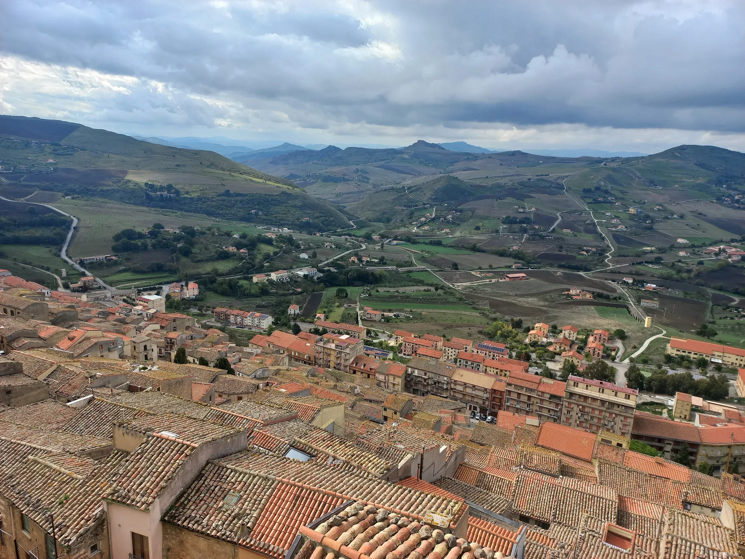 Le campagne coltivate intorno a Gangi viste dall'alto, oltre i tetti del paese, con le colline delle Madonie sullo sfondo