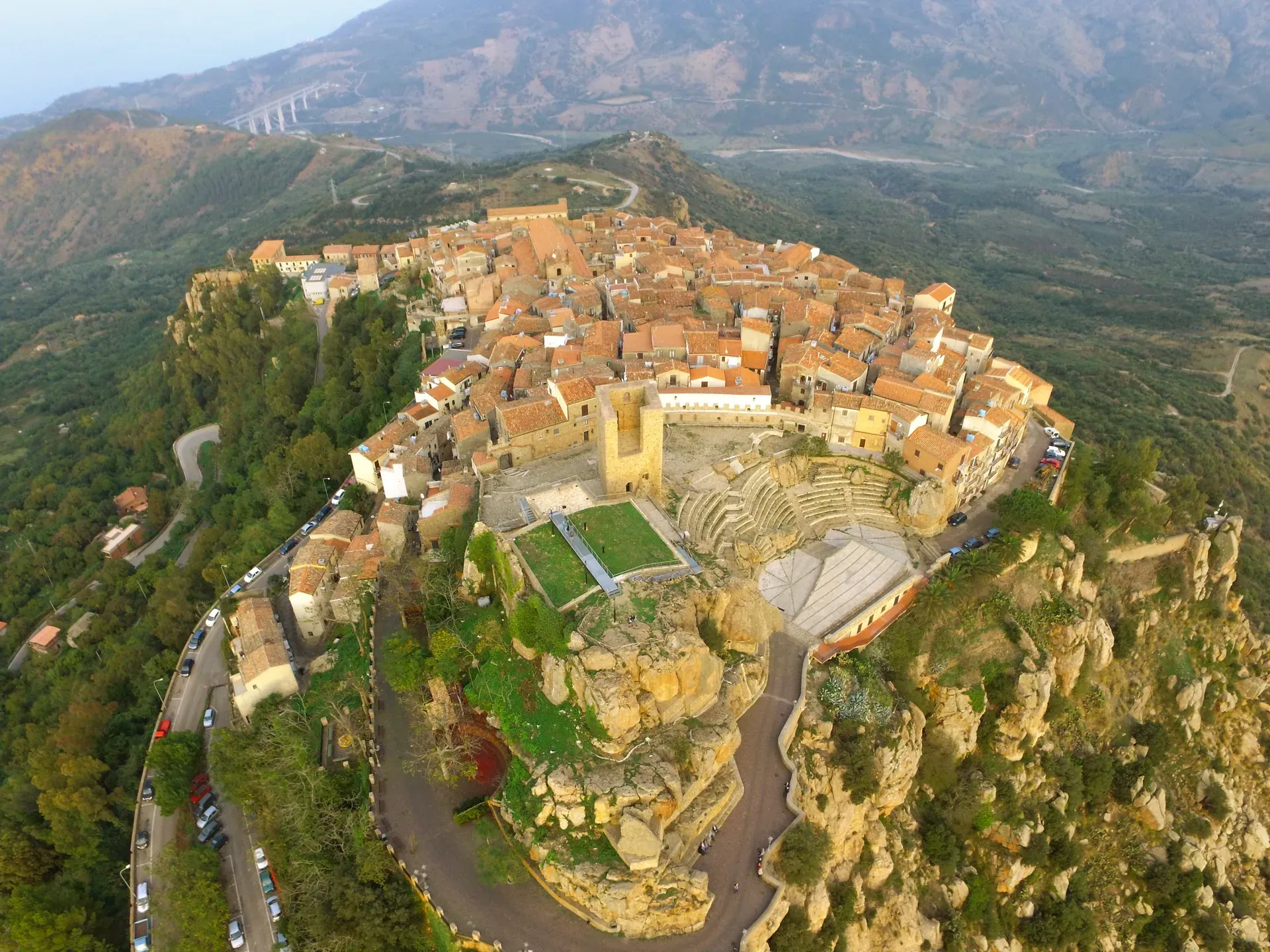 Pollina vista dall’alto, raccolta sulla sua rupe con il teatro di Pietra Rosa