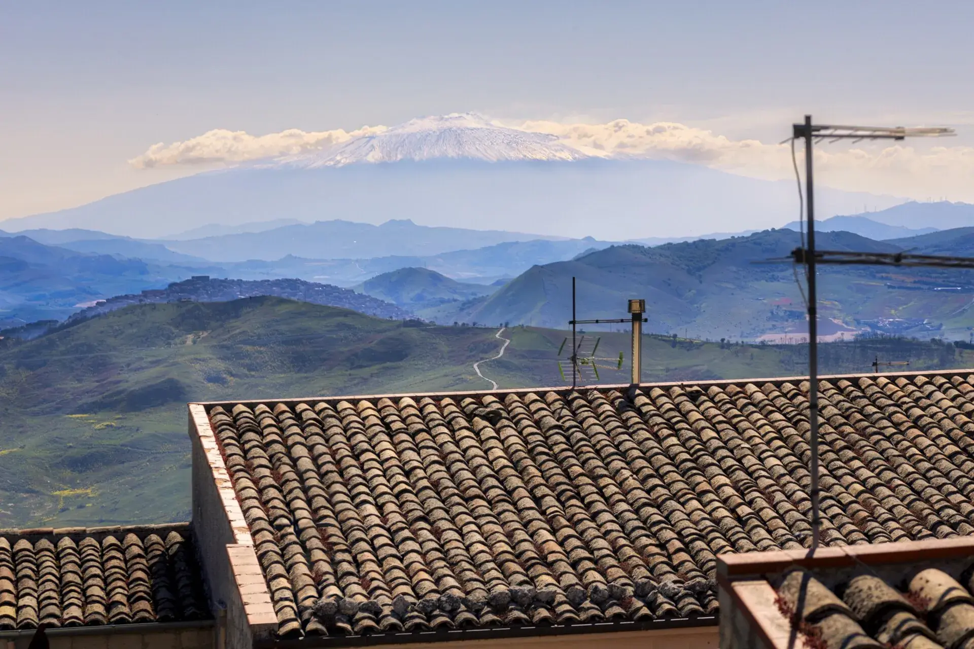 Dai tetti di Petralia Soprana, colline e valli del versante interno delle Madonie con l'Etna innevato sullo sfondo
