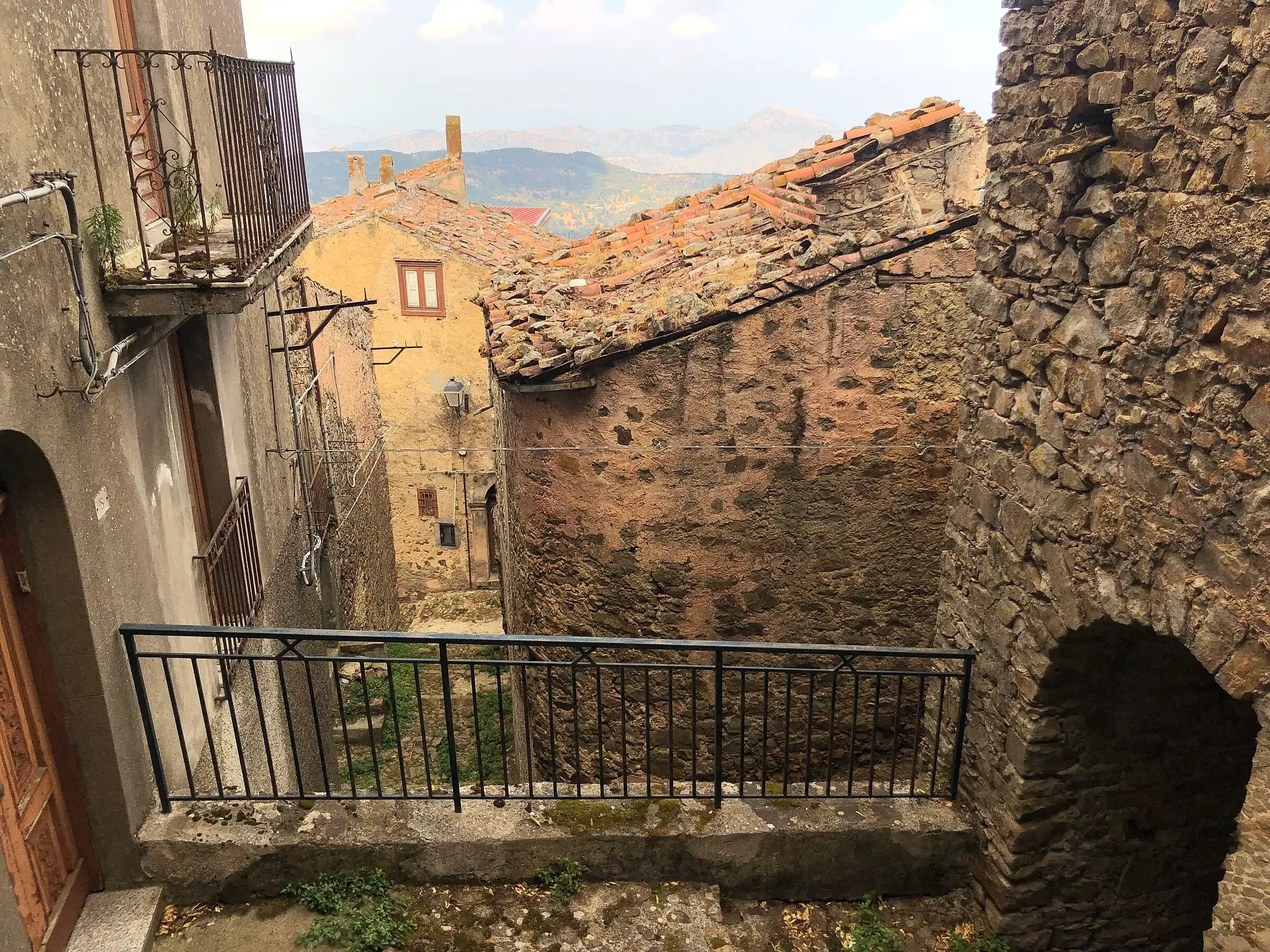 Un vicolo in pietra di San Mauro Castelverde, con i tetti di coppi e le montagne in lontananza
