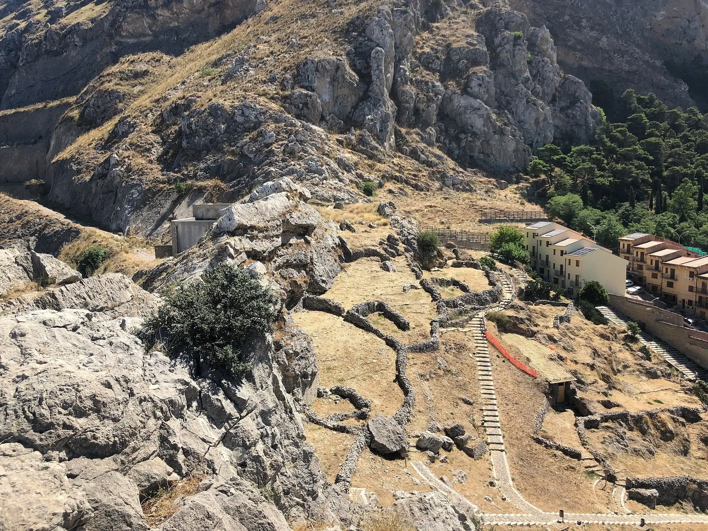 Le pareti calcaree sopra Caltavuturo viste dai ruderi di Terravecchia, con le ultime case del paese e una scalinata