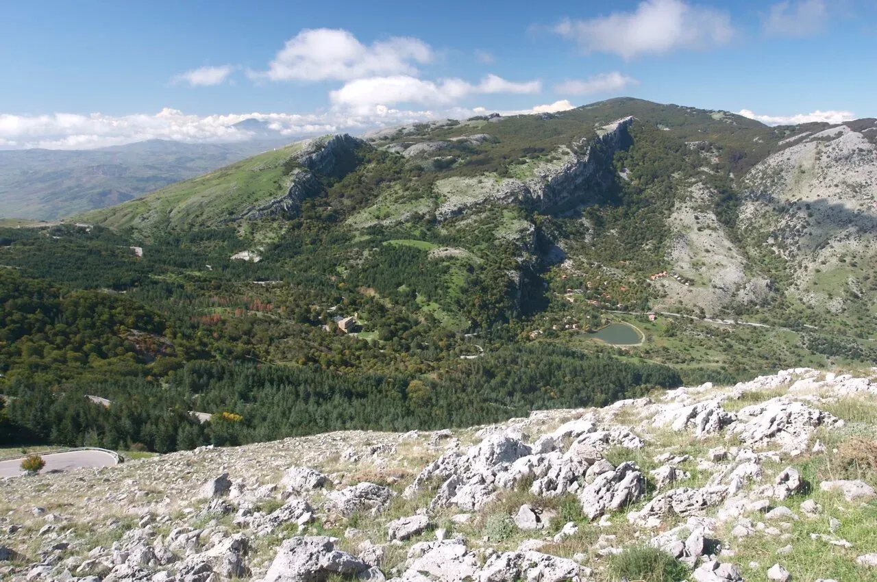 Pietraie di calcare bianco salendo da Piano Battaglia a Pizzo Carbonara, con boschi, un laghetto e le creste sullo sfondo