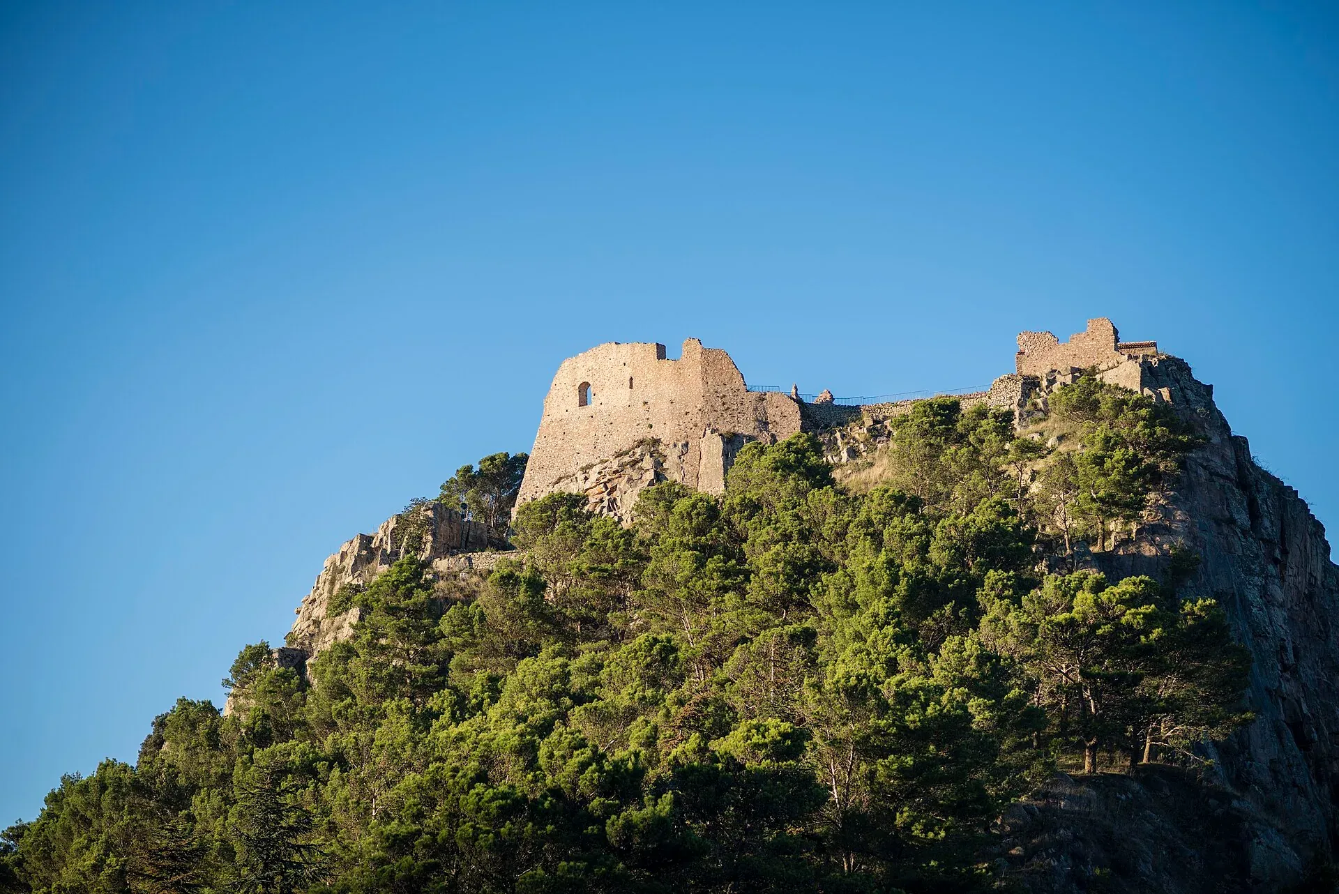 I ruderi del castello dei Ventimiglia in cima alla rocca di Geraci Siculo, sopra un bosco di pini
